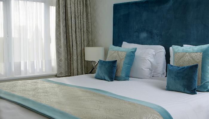 Double bed with white duvet & turquoise blanket & headboard