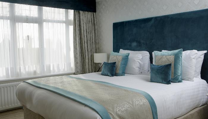Double bed with white duvet & turquoise blanket & headboard 