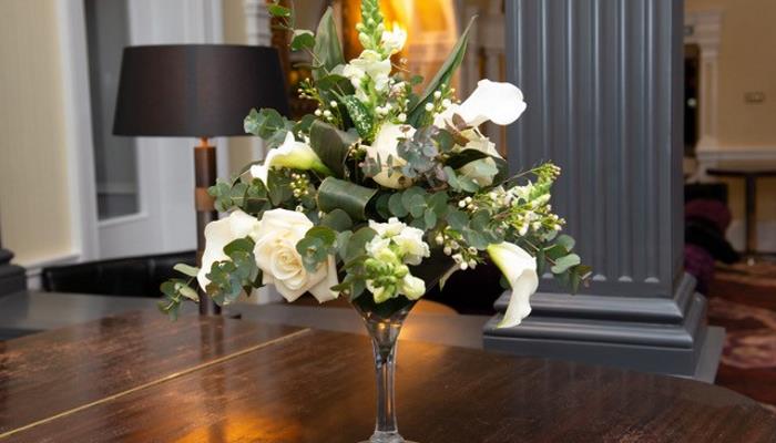 Beautiful bouquet of white roses in a vase on a dark wooden table