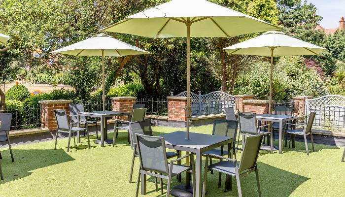 Outdoor dining & drinking area with black tables & chairs each with a white parasol