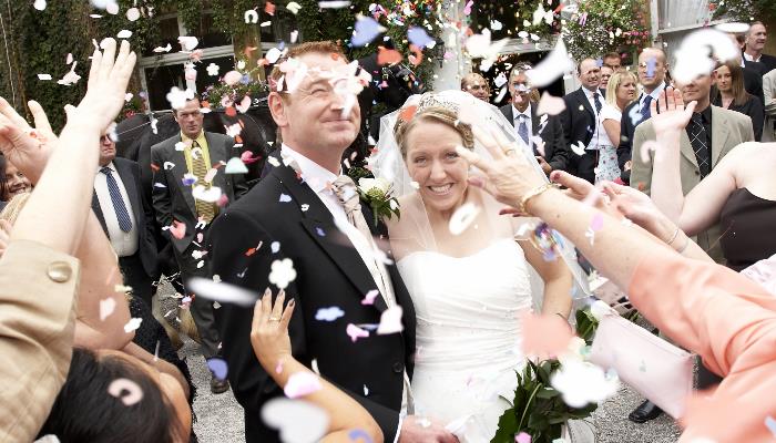 Wedding couple with guests throwing confetti over them